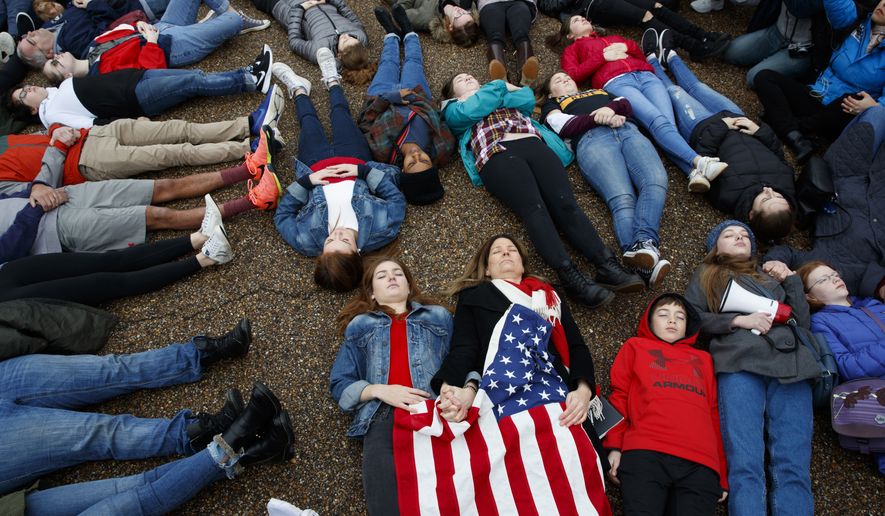Abby Spangler and her daughter Eleanor Spangler Neuchterlein, 16, hold hands as they participate in a &quot;lie-in&quot; during a protest in favor of gun control reform in front of the White House, Monday, Feb. 19, 2018, in Washington. (AP Photo/Evan Vucci)