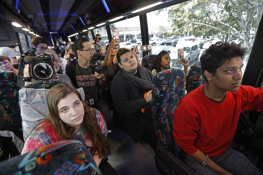 Students who survived the shooting at Stoneman Douglas High School listen to survivors from the Pulse nightclub shooting, after boarding a bus in Parkland, Fla., Tuesday, Feb. 20, 2018. The students plan to hold a rally Wednesday in hopes that it will put pressure on the state's Republican-controlled Legislature to consider a sweeping package of gun-control laws, something some GOP lawmakers said Monday they would consider. (AP Photo/Gerald Herbert)