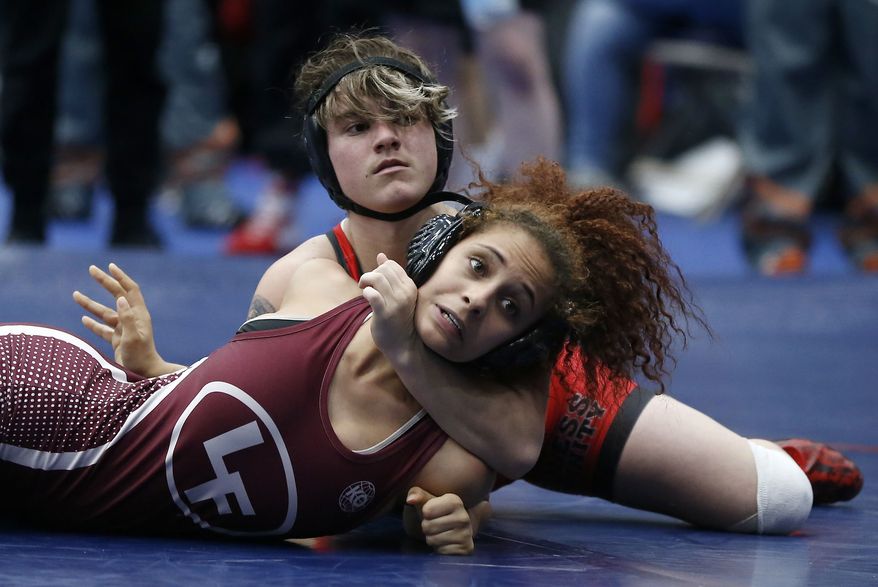 In this Friday, Feb. 16, 2018 photo, Euless Trinity&#39;s Mack Beggs, top, wrestles Lewisville&#39;s Elyse Nelson in the second round of the 110-pound girls division during the 6A Region II wrestling meet at Allen High School in Allen, Texas, Beggs, a senior from Euless Trinity High School near Dallas is transgender and in the process of transitioning from female to male. (Jae S. Lee/The Dallas Morning News via AP)