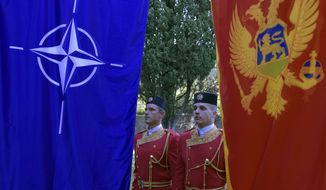 Montenegrin guards of honor stand between NATO, left, and Montenegro flags during ceremony to mark Montenegro&#x27;s accession to NATO, in Podgorica, Montenegro, Wednesday, June 7, 2017. Despite opposition from Russia, Montenegro joined NATO on Monday after completing its membership formalities in Washington. (AP Photo/Risto Bozovic)