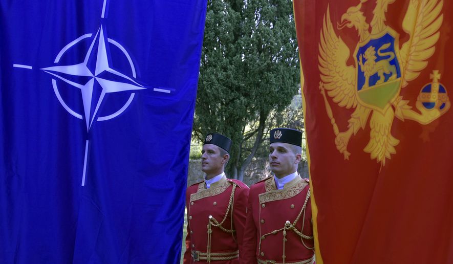 Montenegrin guards of honor stand between NATO, left, and Montenegro flags during ceremony to mark Montenegro's accession to NATO, in Podgorica, Montenegro, Wednesday, June 7, 2017. Despite opposition from Russia, Montenegro joined NATO on Monday after completing its membership formalities in Washington. (AP Photo/Risto Bozovic)