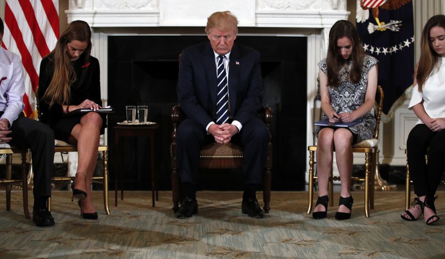President Donald Trump bows his head during an opening prayer at the start of a listening session with high school students and teachers in the State Dining Room of the White House in Washington, Wednesday, Feb. 21, 2018. (AP Photo/Carolyn Kaster)