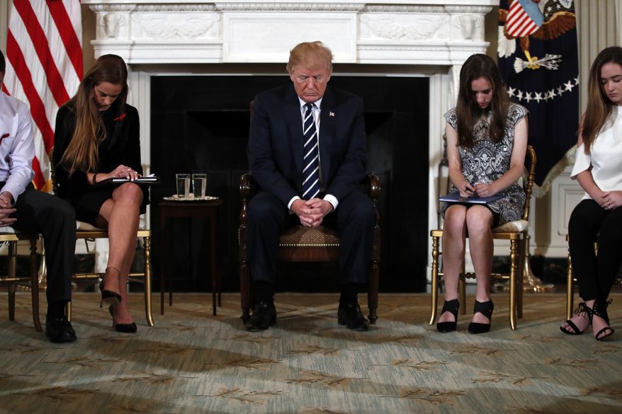 President Donald Trump bows his head during an opening prayer at the start of a listening session with high school students and teachers in the State Dining Room of the White House in Washington, Wednesday, Feb. 21, 2018. (AP Photo/Carolyn Kaster)