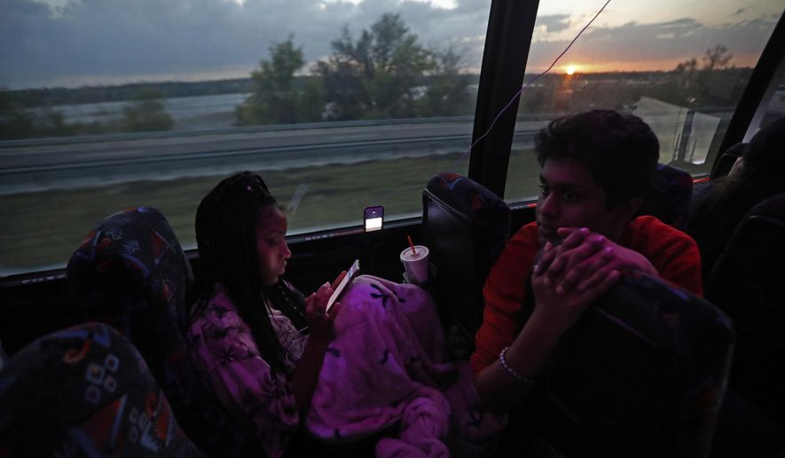 Tyra Hemans, 19, left, and Tanzil Philip, 16, student survivors from Marjory Stoneman Douglas High School, where 17 students and faculty were killed in a mass shooting on Wednesday, converse aboard their bus between Parkland , Fla., and Tallahassee, Fla., Tuesday, Feb. 20, 2018, to rally outside the state capitol and talk to legislators about gun control reform. Nikolas Cruz, a former student, was charged with 17 counts of premeditated murder on Thursday. (AP Photo/Gerald Herbert)