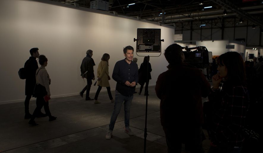 A television journalist reports in front of a blank white wall where art works by artist Santiago Sierra were hung before being taken down in a gallery on the first day of annual the ARCO International Art Fair in Madrid, Spain, Wednesday, Feb. 21, 2018. Madrid's International Art Fair has yanked an exhibition entitled "Political Prisoners in Contemporary Spain," prompting charges of censorship against the government-funded body which operates the event venue. (AP Photo/Paul White)