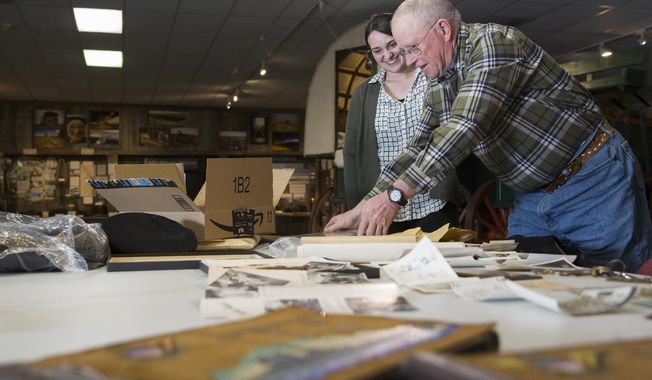 This photo taken Jan. 31, 2018, shows Greg Bennick with Rockpile Museum&#x27;s collections assistant Cara Reeves looking at photos his father Jack Bennick, took during World War II as they choose items to go into the new exhibit &amp;quot;Views of Vanuata: WWII Through the Lens of Jack Bennick&amp;quot;  in Gillette, Wy.  (Kelly Wenzel/Gillette News Record via AP)