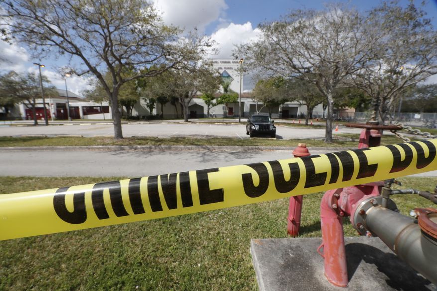 Crime scene tape runs outside Marjory Stoneman Douglas High School in Parkland, Fla., Sunday, Feb. 18, 2018. Authorities opened the streets around the school, which had been closed since a mass shooting on Wednesday. Nikolas Cruz, a former student, was charged with 17 counts of premeditated murder. (AP Photo/Gerald Herbert)