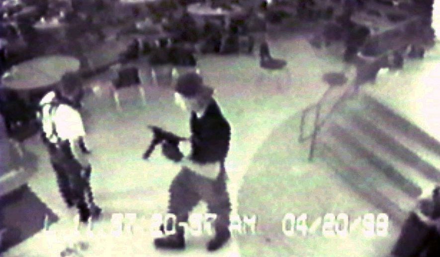 Eric Harris, left, and Dylan Klebold, carrying a TEC-9 semi-automatic pistol, are pictured in the cafeteria at Columbine High School, in Littleton, Colorado, during their April 20, 1999 shooting rampage where they killed a teacher and 12 students. (Associated Press/Jefferson County Sheriff&#x27;s Department)