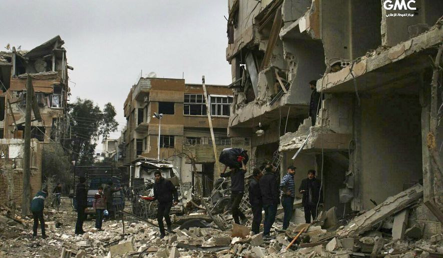 In this photo released on Thursday Feb. 22, 2018 which provided by the Syrian anti-government activist group Ghouta Media Center, which has been authenticated based on its contents and other AP reporting, shows Syrians check their destroyed buildings which attacked during airstrikes and shelling by Syrian government forces, in Ghouta, a suburb of Damascus, Syria. (Ghouta Media Center via AP)