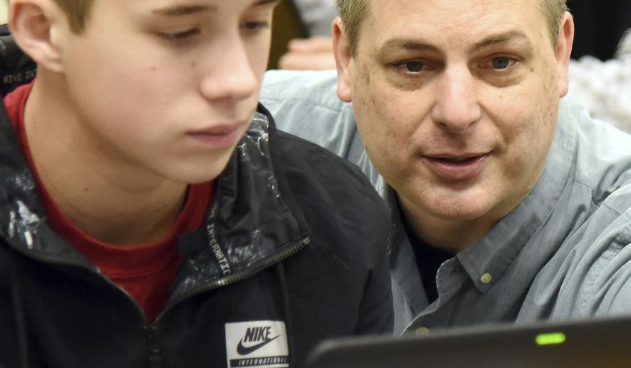In this Jan. 29, 2018 photo, teacher Matt Gain works with eight-grader, Fabian Lewis during  class at Geneva Middle School South, in Geneva, Ill. Gain has taught chemistry and physics at Geneva Middle School South for 17 years and was named the Kane County Educator of the Year in 2017. (Rick West/Daily Herald, via AP)/Daily Herald via AP)