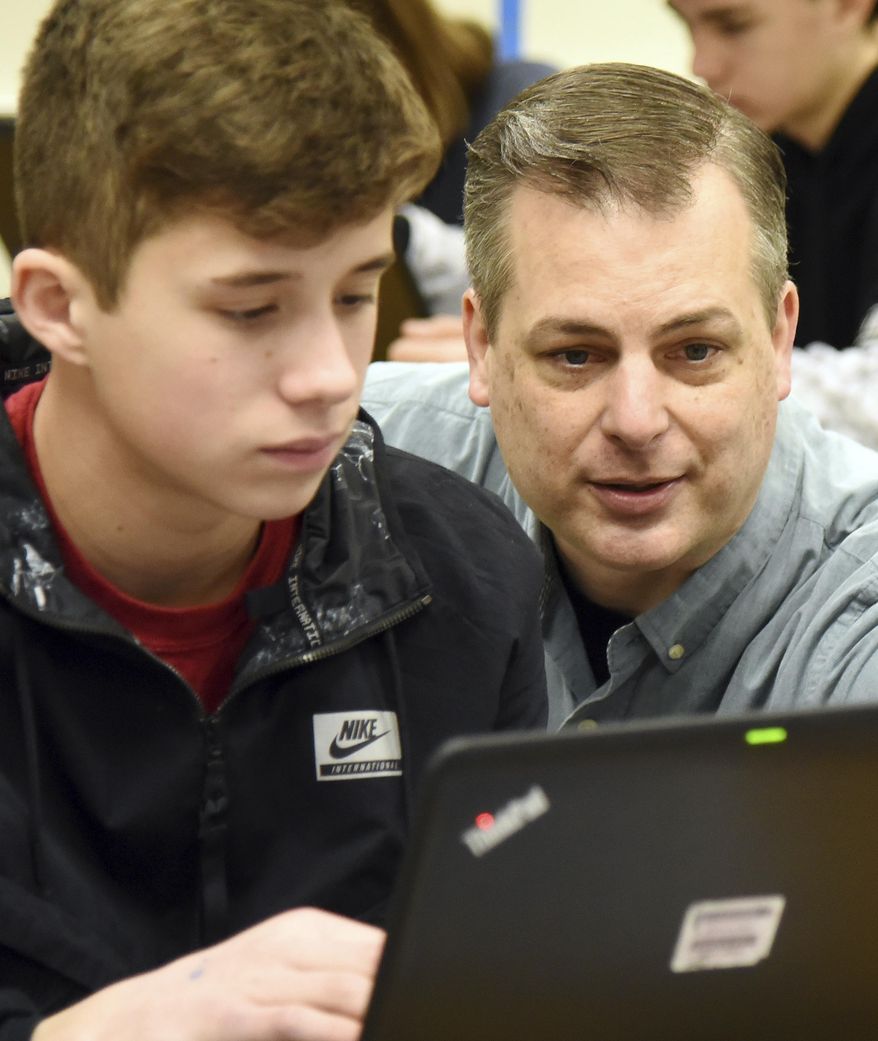 In this Jan. 29, 2018 photo, teacher Matt Gain works with eight-grader, Fabian Lewis during class at Geneva Middle School South, in Geneva, Ill. Gain has taught chemistry and physics at Geneva Middle School South for 17 years and was named the Kane County Educator of the Year in 2017. (Rick West/Daily Herald, via AP)/Daily Herald via AP)