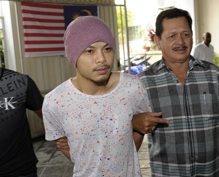 FILE - In this Aug. 22, 2016, file photo, Wee Meng Chee, left, a Malaysian rapper popularly known as Namewee, is escorted by plainclothes policemen on his arrival at the magistrate court in Penang, Malaysia. Malaysian police said in a statement that Wee was detained Thursday, Feb. 23, 2018 after they received four public complaints that his video marking the Chinese year of the dog had “insulted Islam and could negatively impact racial unity and harmony.” (AP Photo/Gary Chuah, File)