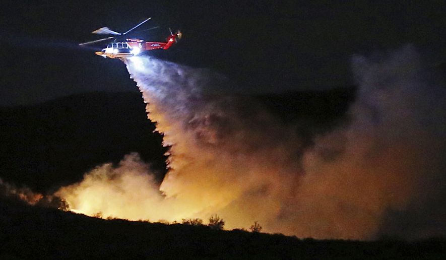 A helicopter makes a water drop on a brush fire that broke out near Temescal Ridge Trail in the vicinity of Skull Rock in a remote section of Topanga State Park in the hills above the Pacific Palisades neighborhood of Los Angeles Wednesday evening, Feb. 21, 2018. No structures are threatened and no evacuations have been called for. (AP Photo/Reed Saxon)