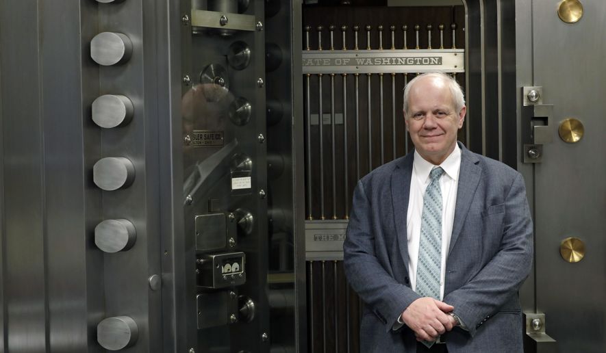 Washington State Treasurer Duane Davidson poses for a photo in front of the state vault,Thursday, Feb. 22, 2018, at the Capitol in Olympia, Wash. Washington state's top finance official wants to use an expected $1.3 billion revenue windfall to pay down the state's growing debt pile. (AP Photo/Ted S. Warren)