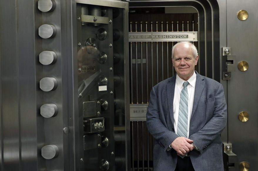 Washington State Treasurer Duane Davidson poses for a photo in front of the state vault,Thursday, Feb. 22, 2018, at the Capitol in Olympia, Wash. Washington state's top finance official wants to use an expected $1.3 billion revenue windfall to pay down the state's growing debt pile. (AP Photo/Ted S. Warren)