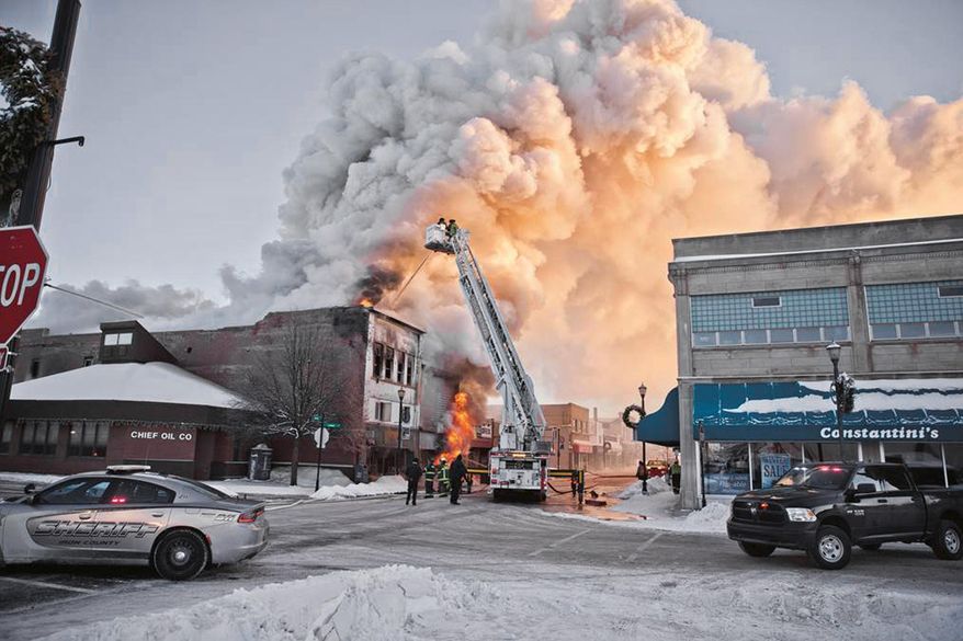 Firefighters battle a fire in downtown Ironwood, Mich., Wednesday, Feb. 21, 2018. The fire claimed at least one life and destroyed two buildings. One of the buildings included two floors of apartments. As of noon, public safety officials wouldn't comment on other injuries, but were working to account for everyone. The cause of the fire remains under investigation. (Jason Juno/The Daily News via AP)