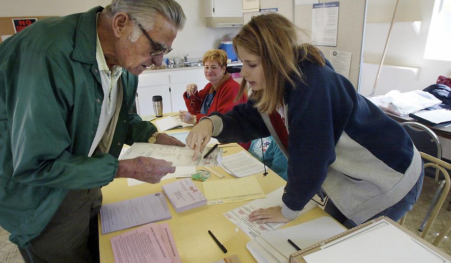 FILE - In this Nov. 2, 2004 file photo, clerk Michelle Gridley, right, assists Bunky Durham as he prepares to cast his ballot at Villa De Oro Recreation Center Club House in Bakersfield, Calif. A federal judge has struck down a redistricting plan for electing supervisors in the county in California's Central Valley. U.S. District Judge Dale Drozd ruled on Friday, Feb. 23, 2018 that election districts in Kern County illegally dilute the voting power of Latinos and deprive them of an opportunity to elect candidates of their choice. (Casey Christie/The Bakersfield Californian via AP, File)