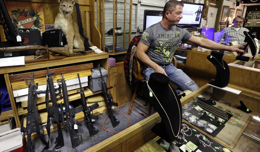 In this photo taken Oct. 20, 2017, Johnny's Auction House owner John West prepares items, including a line of assault rifles behind, for auction where the company handles gun sales for both civilians and a half dozen police departments and the Lewis County Sheriff's Office, in Rochester, Wash. When Washington state and other law enforcement agencies across the country sell guns they've confiscated during criminal investigations, they're not just selling pistols and hunting rifles, they're also putting assault weapons, including AR-15s, back on the street. (AP Photo/Elaine Thompson)