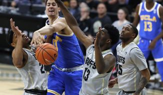 UCLA forward Alex Olesinski, second from left, fights for control of a rebound with, from left to right, Colorado guards George King, Namon Wright and Dominique Collier in the first half of an NCAA college basketball game Sunday, Feb. 25, 2018, in Boulder, Colo. (AP Photo/David Zalubowski)