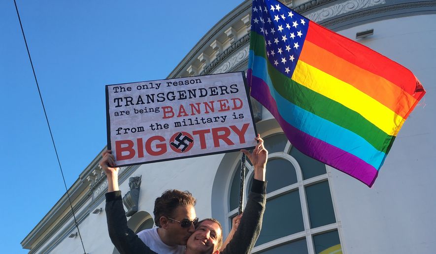 Nick Rondoletto, left, and Doug Thorogood, a couple from San Francisco, wave a rainbow flag and hold a sign against a proposed ban of transgendered people in the military at a protest in the Castro District, Wednesday, July 26, 2017, in San Francisco. Demonstrators flocked to a plaza named for San Francisco gay-rights icon Harvey Milk to protest President Donald Trumps abrupt ban on transgender troops in the military. (AP Photo/Olga R. Rodriguez)