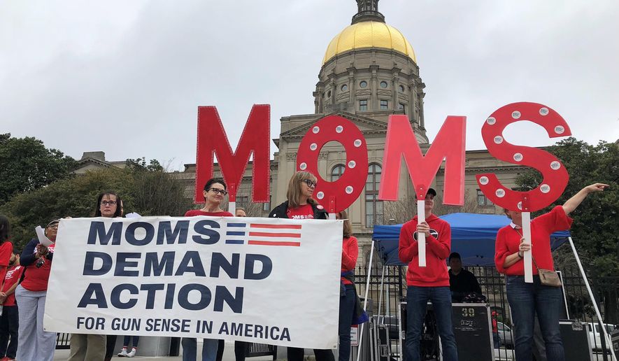 Volunteers with the advocacy group Moms Demand Action for Gun Sense in America hold a banner during a demonstration to lobby the legislature for stricter gun laws, in front of the Georgia Capitol on Wednesday, Feb. 21, 2018, in Atlanta. (AP Photo/Benjamin Nadler)