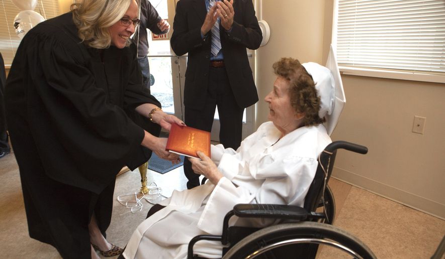 Shannon Ketelhut, Lake Shore Public Shools board president, presents a high school diploma to Ruth Osterman Frezza, 98, on Sunday, Feb. 25, 2018, at her nursing home in Mt. Clemens, Mich., where Lake Shore Public Schools held a graduation ceremony officially welcoming Frezza to the Class of 38. Ruth should have been a member of the Class of 1938, but had to leave school in 1936 to take care of her siblings.  (Sheila Springsteen/Detroit News via AP)