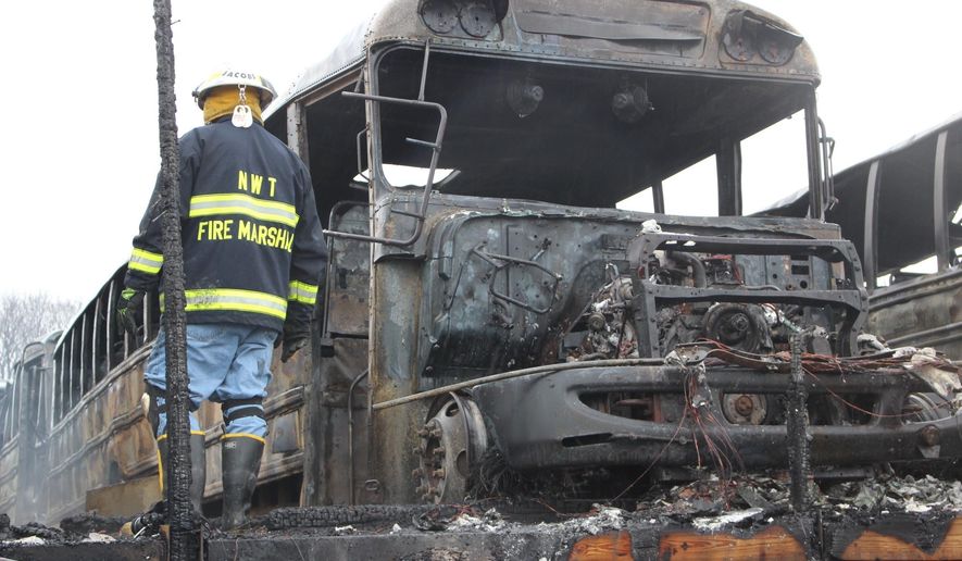 A firefighter clears wreckage from a school bus depot in South Whitehall, Pa.,, that was destroyed by fire ion Friday, Feb. 23, 2018. Jeff Johnson, chief of the Tri-Clover Fire Co., said 16 buses inside the building were destroyed, and a dozen outside the building received damage that ranged from blistered paint to broken windshields. The 25 destroyed or damaged buses represent about 25 percent of the district's fleet. No injuries were reported, and the cause of the fire remained under investigation. (AP Photo/Michael Rubinkam)