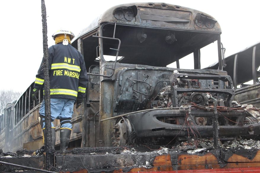 A firefighter clears wreckage from a school bus depot in South Whitehall, Pa.,, that was destroyed by fire ion Friday, Feb. 23, 2018. Jeff Johnson, chief of the Tri-Clover Fire Co., said 16 buses inside the building were destroyed, and a dozen outside the building received damage that ranged from blistered paint to broken windshields. The 25 destroyed or damaged buses represent about 25 percent of the district's fleet. No injuries were reported, and the cause of the fire remained under investigation. (AP Photo/Michael Rubinkam)