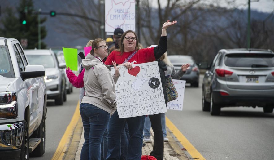 Amanda Scarbery waves to passing drivers while demonstrating with other school personnel along Route 60 across from the capitol building in Charleston, W.V., on Monday, February 26, 2018 during the third day of the statewide walkout by school personnel.  (Craig Hudson /Charleston Gazette-Mail via AP)