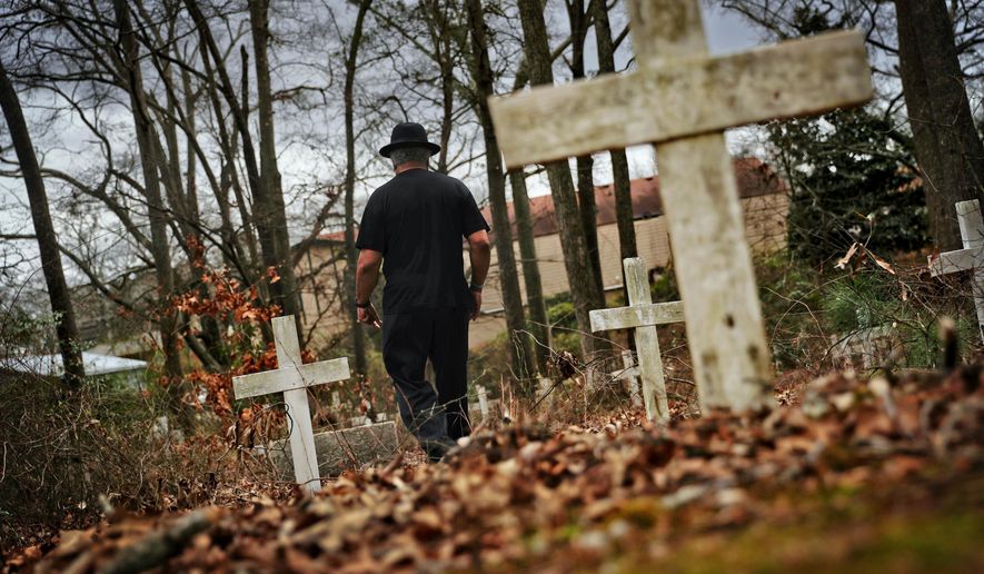 Tyrone Brooks, a veteran civil rights activist, walks through a historic African American cemetery where unknown graves are marked with white crosses and where one of the 1946 lynching victims is buried in Monroe, Ga., Thursday, Feb. 22, 2018. Law enforcement revisited the case in the 1990s after people came forward promising new information, though investigators said they still couldn't prosecute anyone. In June 2000, then-Gov. Roy Barnes ordered the Georgia Bureau of Investigation to reopen the case. That investigation closed in January and the bureau made public its redacted case file, including interviews, leads followed, case summaries and press clippings. (AP Photo/David Goldman)