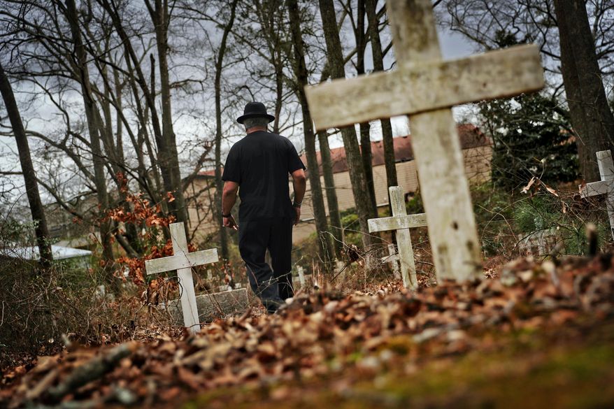 Tyrone Brooks, a veteran civil rights activist, walks through a historic African American cemetery where unknown graves are marked with white crosses and where one of the 1946 lynching victims is buried in Monroe, Ga., Thursday, Feb. 22, 2018. Law enforcement revisited the case in the 1990s after people came forward promising new information, though investigators said they still couldn't prosecute anyone. In June 2000, then-Gov. Roy Barnes ordered the Georgia Bureau of Investigation to reopen the case. That investigation closed in January and the bureau made public its redacted case file, including interviews, leads followed, case summaries and press clippings. (AP Photo/David Goldman)