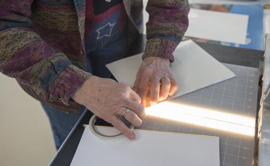 Kathy Downey attaches adhesives to the spine of her book pages as she creates a memory book on Thursday, Feb. 22, 2018, in Gillette, Wyo. (Kelly Wenzel/Gillette News Record via AP)