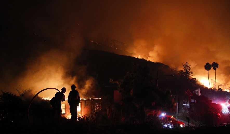 File - In this Dec. 7, 2017 file photo, two firefighters watch as a home burns in a wildfire in La Conchita, Calif. California state agencies spent nearly $1.8 billion fighting fierce wildfires that killed dozens of people and destroyed thousands of homes and businesses last year. Legislative Analyst's Office officials told lawmakers Thursday, March 1, 2018, that the federal government will reimburse most of the costs, but the state will still need to come up with about $371 million. (AP Photo/Jae C. Hong, File)