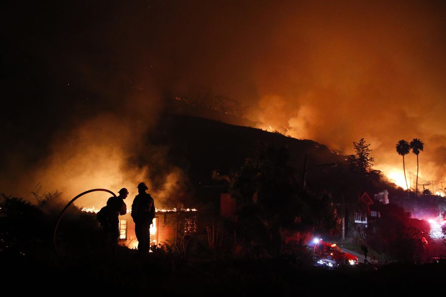 File - In this Dec. 7, 2017 file photo, two firefighters watch as a home burns in a wildfire in La Conchita, Calif. California state agencies spent nearly $1.8 billion fighting fierce wildfires that killed dozens of people and destroyed thousands of homes and businesses last year. Legislative Analyst's Office officials told lawmakers Thursday, March 1, 2018, that the federal government will reimburse most of the costs, but the state will still need to come up with about $371 million. (AP Photo/Jae C. Hong, File)