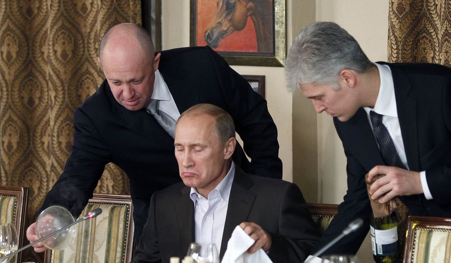 FILE - In this Friday, Nov. 11, 2011 file photo, businessman Yevgeny Prigozhin, left, serves food to Russian Prime Minister Vladimir Putin, center, during dinner at Prigozhin&#39;s restaurant outside Moscow, Russia. U.S. indictment charged 13 Russians with running a hidden social media trolling campaign in a bid to disrupt the 2016 U.S. presidential election. (AP Photo/Misha Japaridze, Pool, File) **FILE**