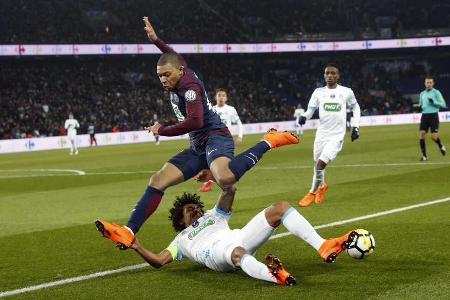 PSG's Kylian Mbappe challenges for the ball with Marseille's Luiz Gustavo Dias during the French Cup soccer match between Paris Saint-Germain and Marseille at the Parc des Princes Stadium, in Paris, France, Wednesday, Feb. 28, 2018. (AP Photo/Thibault Camus)
