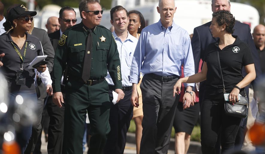 FILE - In this Feb. 15, 2018, file photo, Florida Gov. Rick Scott, second from right, and Broward County Sheriff Scott Israel, second from left, walk to a news conference, in Parkland, Fla., to speak about the shooting the day before at Marjory Stoneman Douglas High School. Photographs of the Florida sheriff with one of his deputies, a Muslim American, prompted many sites’ false claims that Israel had terror ties. The stories appeared alongside criticism of the office’s response to the school shooting that killed 17 people. (AP Photo/Wilfredo Lee, File)