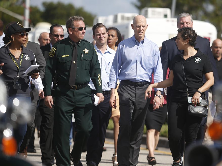 FILE - In this Feb. 15, 2018, file photo, Florida Gov. Rick Scott, second from right, and Broward County Sheriff Scott Israel, second from left, walk to a news conference, in Parkland, Fla., to speak about the shooting the day before at Marjory Stoneman Douglas High School. Photographs of the Florida sheriff with one of his deputies, a Muslim American, prompted many sites’ false claims that Israel had terror ties. The stories appeared alongside criticism of the office’s response to the school shooting that killed 17 people. (AP Photo/Wilfredo Lee, File)