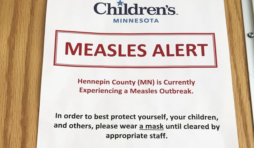 FILE - In this Tuesday, May 2, 2017 file photo, a sign at the specialty clinic at Children&#x27;s Minnesota in Minneapolis, alerts patients to a measles outbreak in the area. While parts of the world have all but banished measles, Europe is still getting hit with large outbreaks where some people don’t get vaccinated. (AP Photo/Amy Forliti, file)
