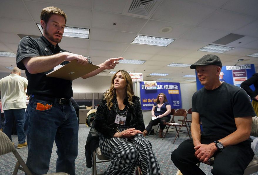 In this Wednesday, Feb. 28, 2018 photo, United Way's Christopher Mackey, left, role plays a police officer as he detains Erika Willis, middle, the executive director of Tumbleweed, and Steve Restad, a volunteer, for a simulated drug deal during the poverty simulation at United Way of Yellowstone County, Mont. Pretend money, families and events all played a role in a United Way of Yellowstone County simulation designed to offer insights into the lives of Americans struggling to get by. (Bethany Baker/The Billings Gazette via AP)