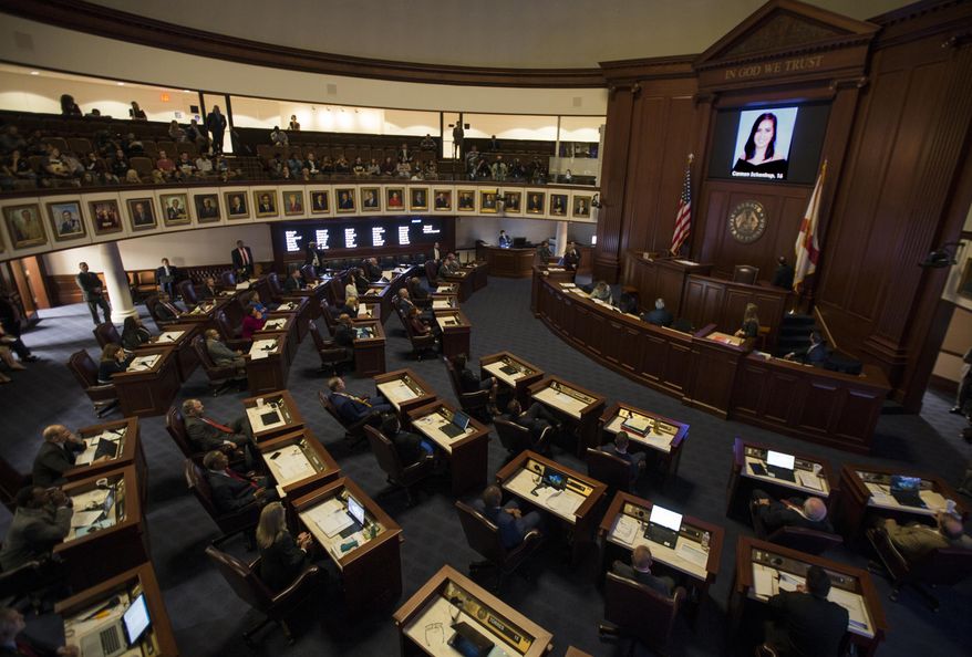 FILE - In this Feb. 21, 2018, file photo, the Florida Senate chamber is darkened while a slideshow shows each person killed in a shooting at Marjory Stoneman Douglas High School, at the state Capitol in Tallahassee, Fla. The Florida Senate spent hours debating a bill to increase school safety and restrict gun purchases in a rare Saturday session, March 3, that often turned into a debate on gun control and arming teachers in the aftermath of last month's Parkland school shootings. (AP Photo/Mark Wallheiser, File)