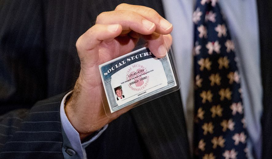 William Wachtel holds up a mock Social Security card of President-elect Donald Trump as he speaks to members of the media following a meeting with Trump at Trump Tower in New York, Monday, Jan. 16, 2017. (AP Photo/Andrew Harnik)