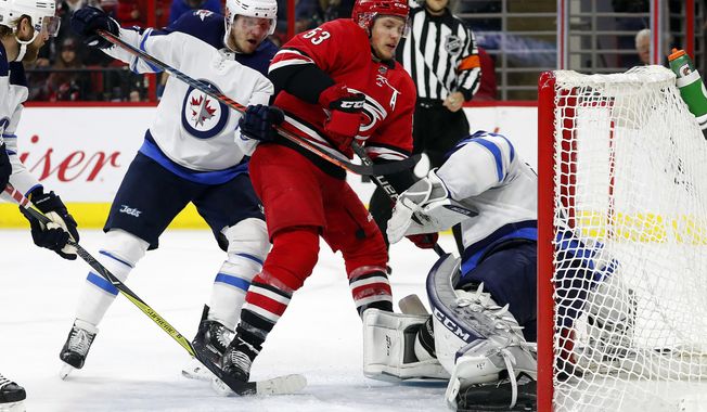 Carolina Hurricanes&#x27; Jeff Skinner (53) is pushed into Winnipeg Jets goaltender Connor Hellebuyck (37) by Jets&#x27; Dmitry Kulikov (5) during the second period of an NHL hockey game, Sunday, March 4, 2018, in Raleigh, N.C. (AP Photo/Karl B DeBlaker)
