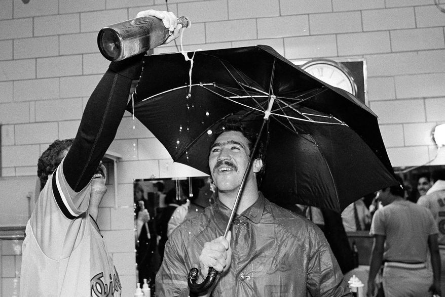 FILE - In this Sept. 25, 1983, file photo, Baltimore Orioles pitcher Sammy Stewart, right, uses an umbrella to keep dry as teammate Bill Swaggerty pours a beverage during their victory celebration after defeating the Milwaukee Brewers to win the American League Eastern Division title in Milwaukee, Wis. Stewart, who helped the Orioles win the 1983 World Series before falling into a life of drug addiction and arrests, has died. He was 63. The Henderson County Sheriff's Office said Stewart was found dead Friday, March 2, 2018, at a residence. No cause for his death had been determined as of Sunday. (AP Photo/Tom Lynn, File)