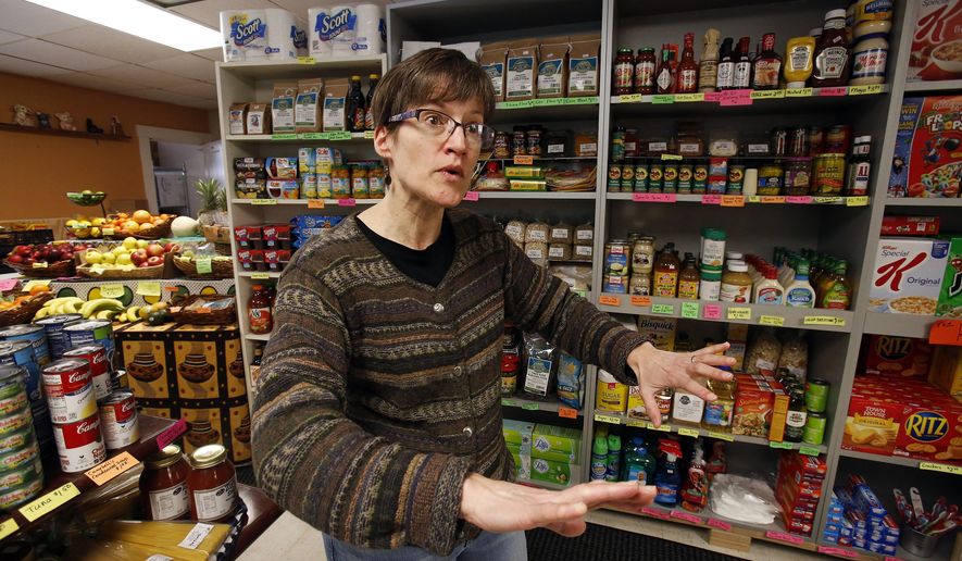In this Feb. 26, 2018 photo, Dianne Shenk talks to a customer in her Dylamatos Market in Hazelwood, Pa. About a quarter of Shenk's customers pay with benefits from the federal Supplemental Nutrition Assistance Program, so the government's proposal to replace the debit card-type program with a pre-assembled box of shelf-stable goods delivered to recipients concerns her and other grocery operators in poor areas. "These boxes will be full of shelf-stable items, the same things we're being told not to eat," she said. (AP Photo/Gene J. Puskar)