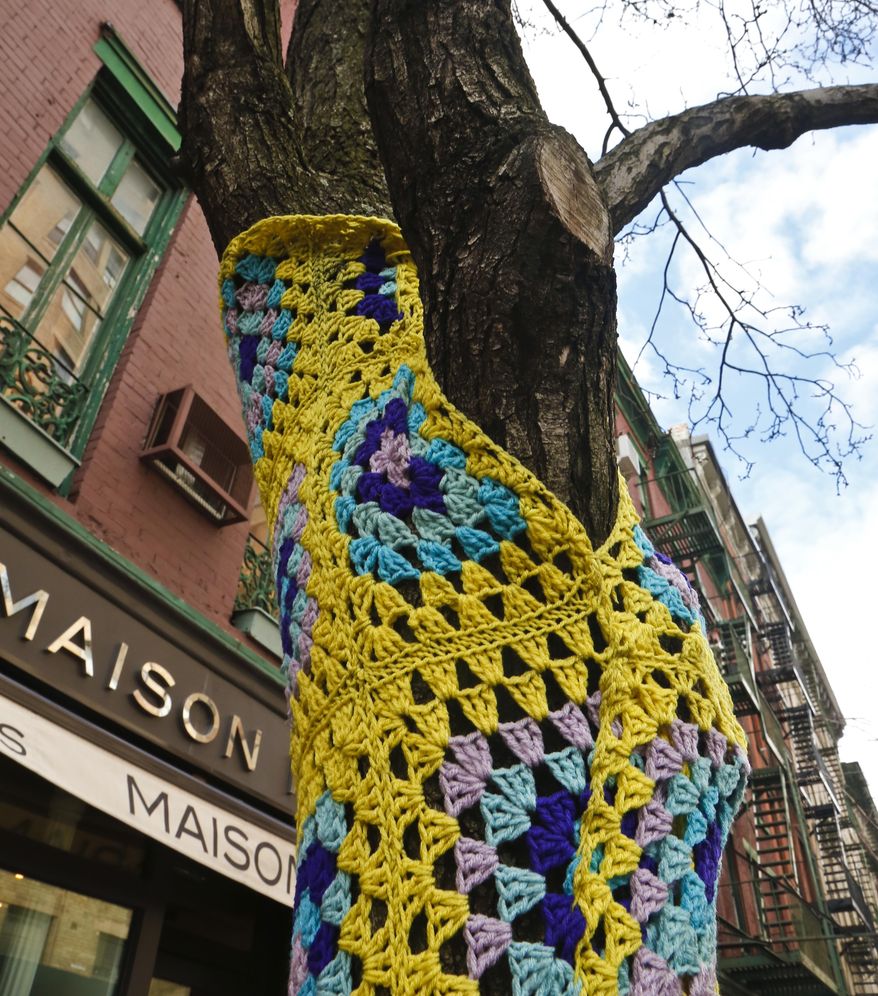 One of more than a dozen trees on Christopher Street is shown decorated in crocheted patterns, Monday March 5, 2018, in New York. The New York City Parks Department says a cluster of trees in the West Village neighborhood can keep their crocheted art after residents of the neighborhood said that it increased business and foot traffic. (AP Photo/Bebeto Matthews)