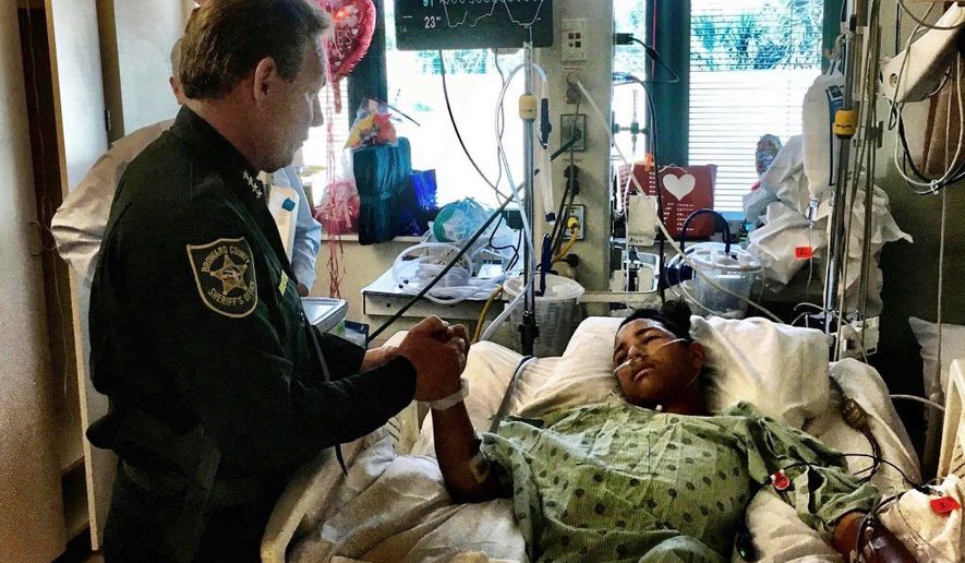 This image made available by the Broward County Sheriff&#x27;s Office on Sunday, Feb. 18, 2018, shows Sheriff Scott Israel, holding the hand of Anthony Borges, 15, a student at Marjory Stoneman Douglas High School. The teenager was shot five times during the massacre on Valentine&#x27;s Day that killed 17 students. Borges is being credited with saving the lives of at least 20 other students. (Broward County Sheriff&#x27;s Office via AP)