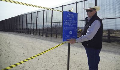 This photo provided by the New Mexico State Land Office shows New Mexico Land Commissioner Aubrey Dunn installing a sign along the U.S.-Mexico border to indicate the land belongs to the state Tuesday, March 6, 2018, near Santa Teresa, N.M. New Mexico&#39;s top land manager posted signs along the U.S.-Mexico border aimed at blocking border patrol operations on a one-mile stretch of state trust land over concerns that the federal government is not compensating the state for using the land. (Kris McNeil/New Mexico State Land Office via AP)