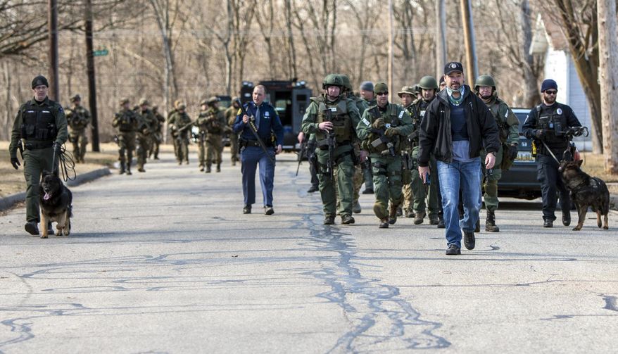 FILE - In this March 2, 2018, file photo, police search for James Eric Davis Jr. in local neighborhoods after a fatal shooting at Central Michigan University's Campbell Hall in Mount Pleasant, Mich. The student accused of killing his parents inside a dorm room is hospitalized but scheduled to appear in court via video for an arraignment hearing Tuesday, March 6. Davis was arrested early Saturday following a daylong manhunt. (Cory Morse/The Grand Rapids Press-MLive.com via AP, File)