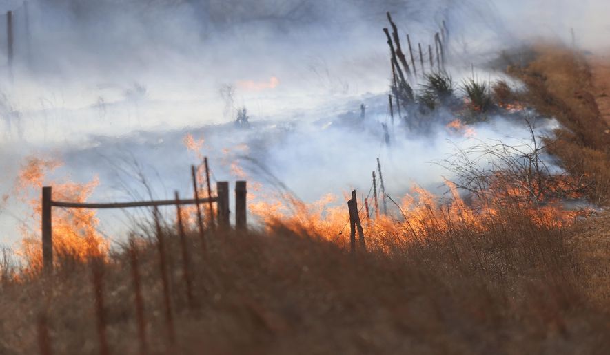 Firefighters battle a fire north of Harper, Kans., Tuesday, March 6, 2018. Flames driven by winds gusting up to 50 mph hamper efforts of units from several surrounding towns. (Bo Rader/The Wichita Eagle via AP)